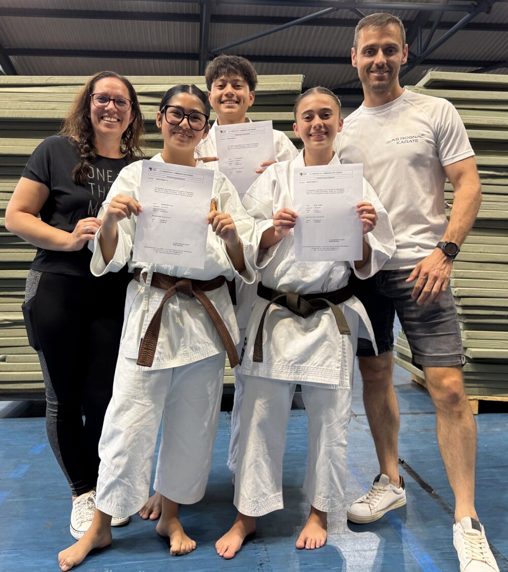 Lily, Laura et Baptiste, diplôme de ceinture noire en main, entourés de leurs enseignants sur le tatami.